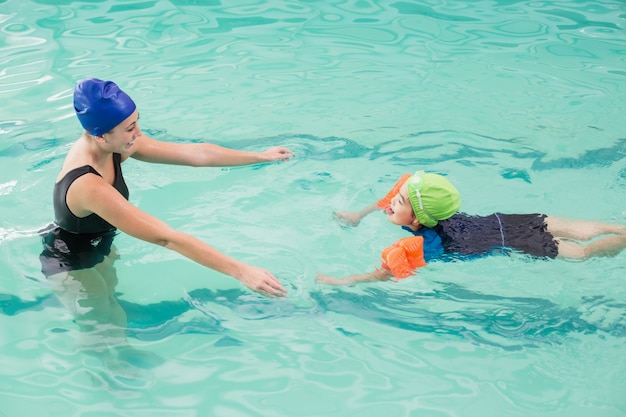 Cute little boy learning to swim with coach