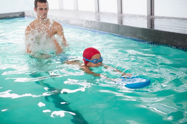 Cute little boy learning to swim with coach