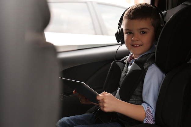 Cute little boy listening to audiobook in car