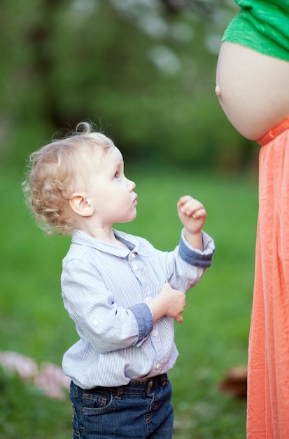 Симпатичный маленький мальчик, глядя на беременных мам живот