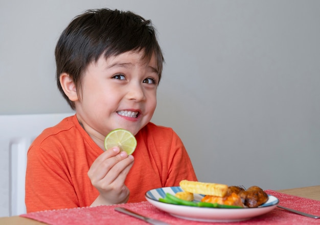 Cute little boy makes funny face after tasting a sour lemon