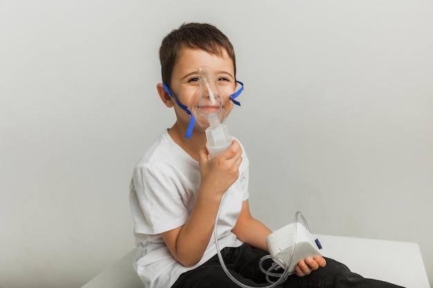 Cute little boy makes inhalation. The child holds an inhaler in his hand and is being treated for a cough. high quality studio photo.