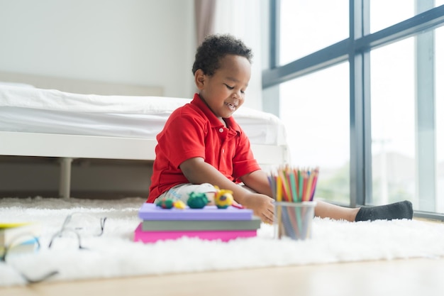 Cute little boy making things from plasticine on the ground Follow your imagination with a smiling