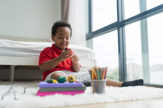 Cute little boy making things from plasticine on the ground Follow your imagination with a smiling