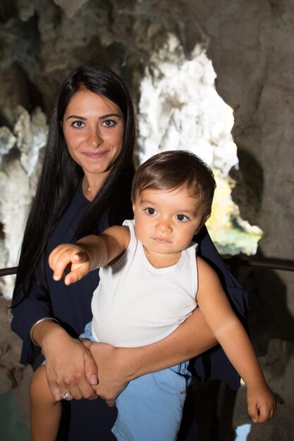 Foto ragazzino sveglio nelle braccia della madre all'aperto durante il giorno di vacanza