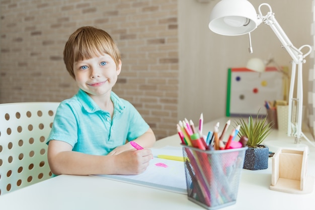 Cute little boy painting with color pencils at home