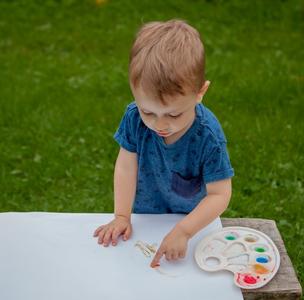 Cute little boy painting with hands using gauche paints