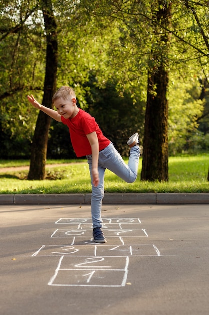 Cute little boy playing hopscotch outdoor. Street children's games. Selective focus.