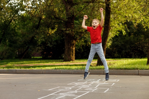 Cute little boy playing hopscotch outdoor. Street children's games. Selective focus.