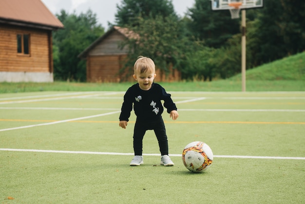 Foto ragazzino sveglio che gioca a calcio con una palla