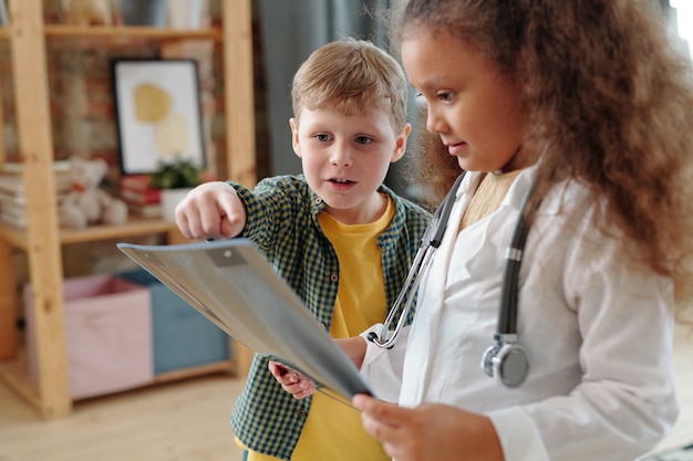 Cute little boy pointing at x-ray image while playing doctor with friend