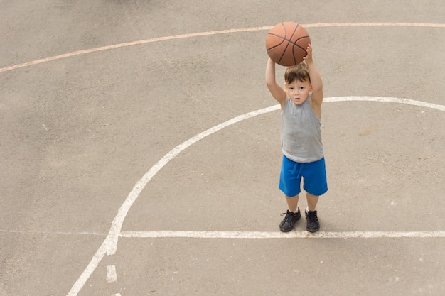 Cute little boy practising on a basketball court