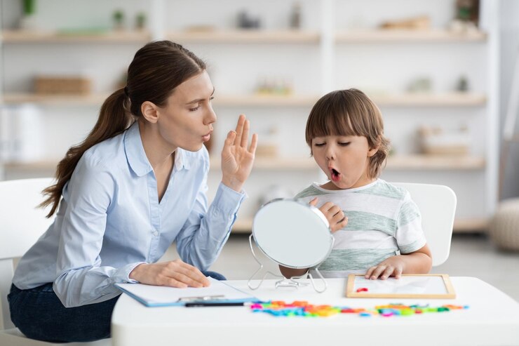 Photo cute little boy pronouncing sound o looking at mirror professional woman therapist teaching kid