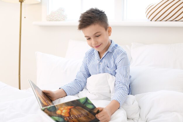 Cute little boy reading bedtime story at home