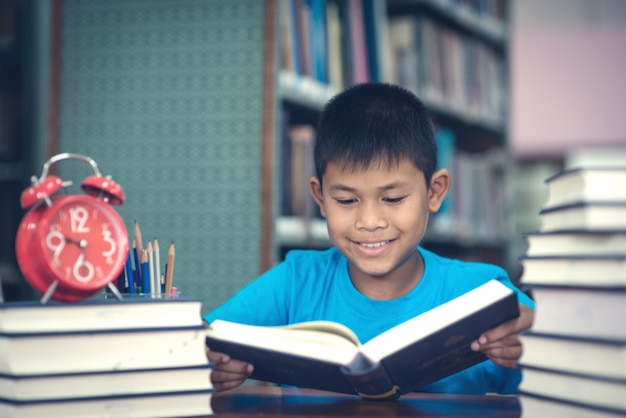 도서관에서 귀여운 작은 소년 읽기 책