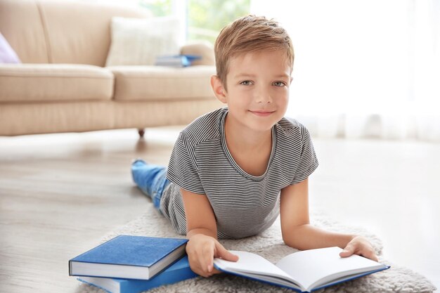 Cute little boy reading on floor at home