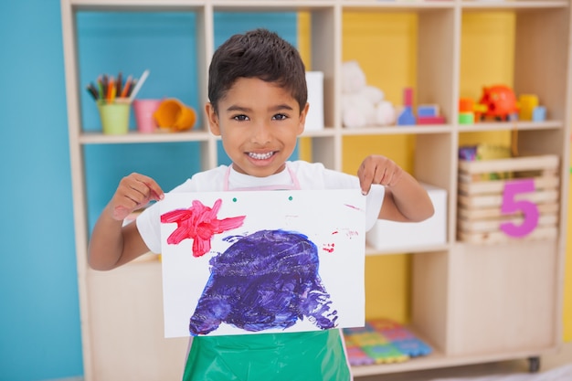 Photo cute little boy showing his painting in classroom