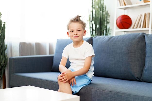 Cute little boy sitting on couch at home, looking at camera, portrait