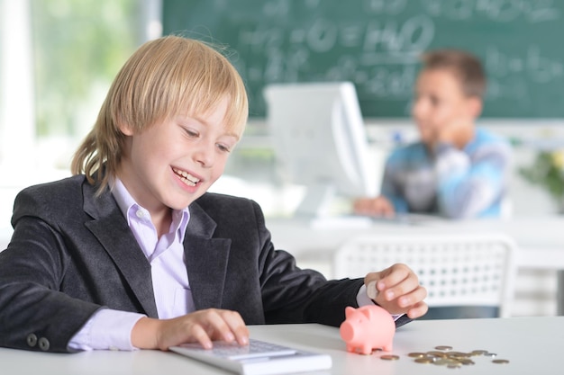 Cute little boy sitting at table with laptop while doing homework