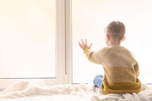 Premium Photo | Cute little boy sitting on windowsill