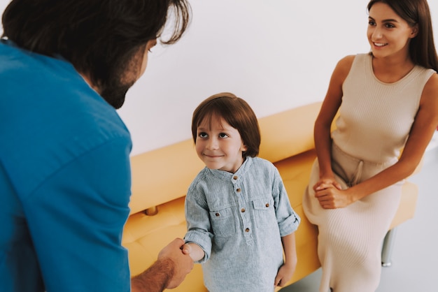 Little boy sveglio che sorride al medico e al handshake