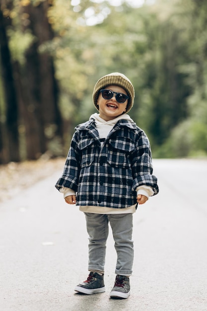 Photo cute little boy standing on the road in park