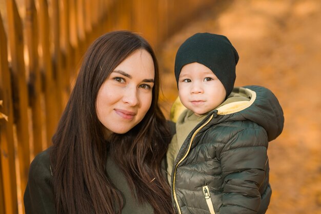 Фото Милый маленький мальчик стоит с матерью на улице счастливый ребенок гуляет в осеннем парке маленький мальчик носит модную куртку и шляпу осенняя мода стильный ребенок на улице