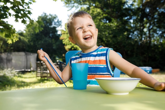 Милый мальчик трех лет ест кукурузные хлопья на улице
