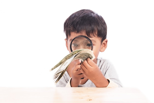 Cute little boy use magnifier looking money