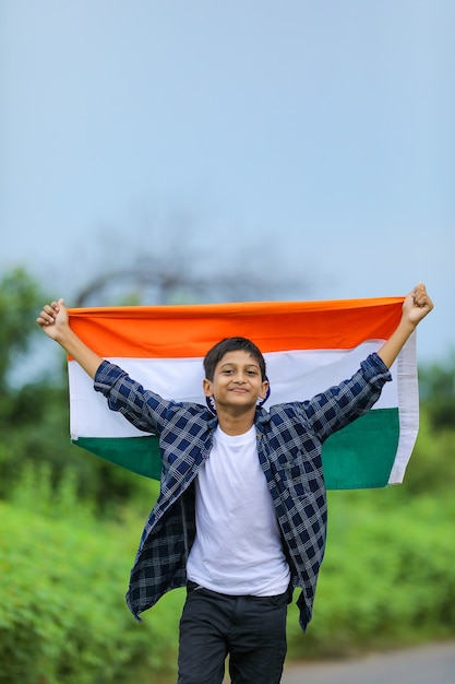 Cute little boy waving Indian National Tricolor Flag over nature background