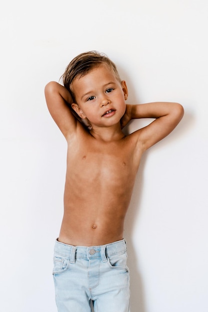 Photo cute little boy wearing blue jeans posing against white background like fashion model