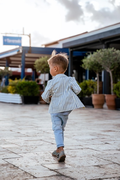 Cute little boy wearing stylish clothes walking down the street