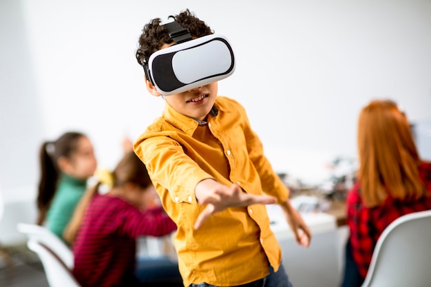 Милый маленький мальчик в очках виртуальной реальности VR в классе робототехники