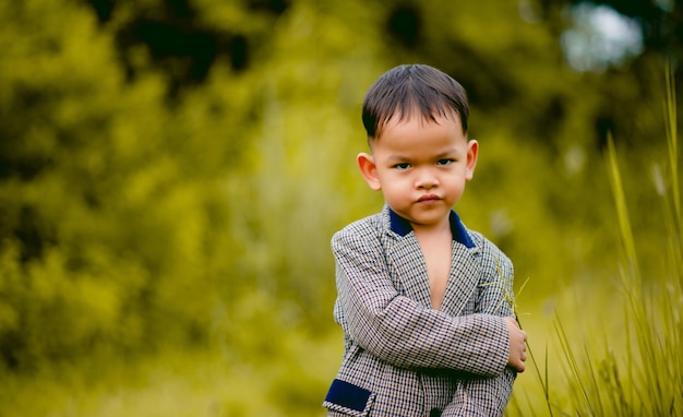 かわいい男の子 芝生のある裏庭でスーツを着て、何か面白いものを探している身なりの良い少年