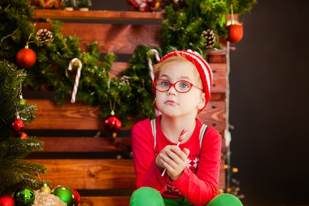 Cute little boy with blonde hair, blue eyes and glasses with christmas candy