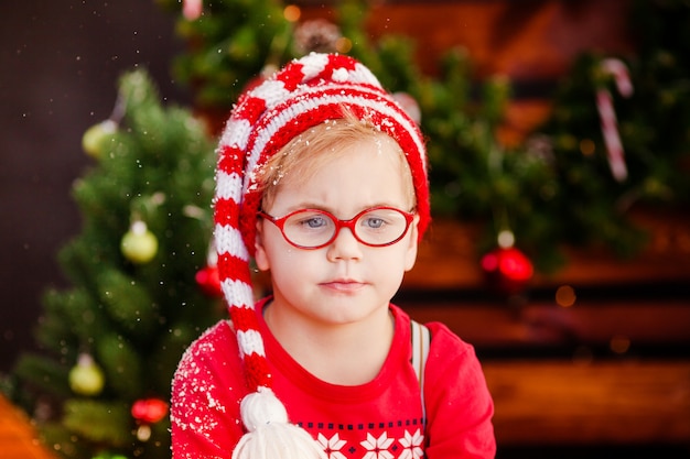 Cute little boy with blonde hair, blue eyes and glasses with santa's hat