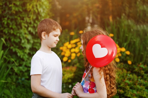 Cute little boy with gift red balloons his friend girl.