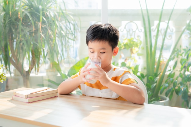 Cute little boy with glass of milk drink at home