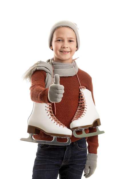 Cute little boy with ice skates showing thumb-up against white