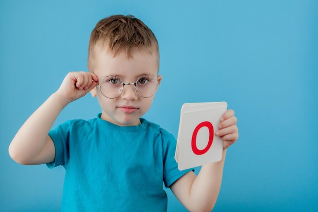 Foto bambino carino con una lettera su sfondo blu bambino che impara un alfabeto