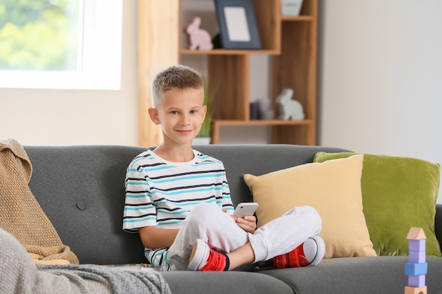 Cute little boy with mobile phone at home