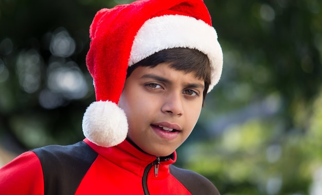 A cute little boy with Santa cap red t-shirt, smiling happily and looking at the camera
 