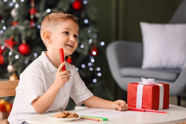 Cute little boy writing letter to Santa at home on Christmas eve