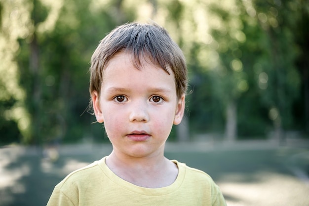 A cute little boy in yellow T-shirt in the football field