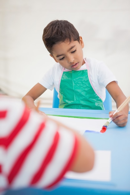 かわいい男の子、教室のテーブルで絵を描く