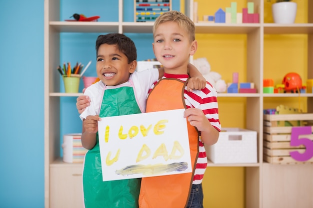 Photo cute little boys showing fathers day painting