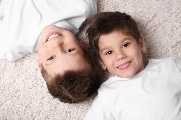 Cute little brothers lying on carpet at home