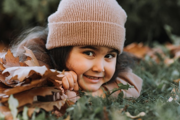 Photo cute little brunette girl lying on the grass in autumn