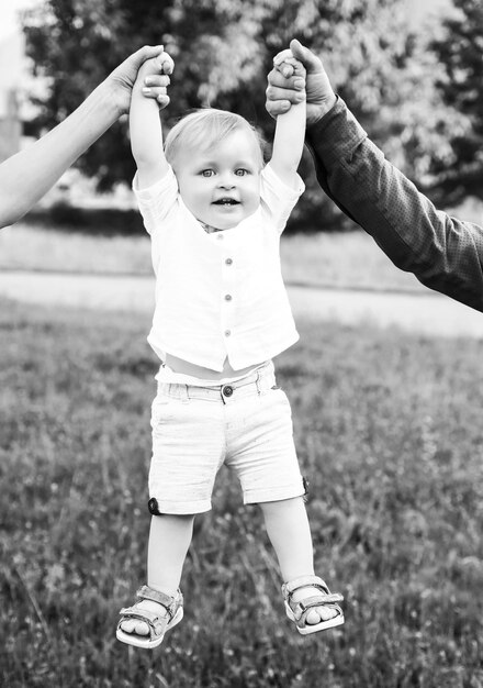 Photo cute little caucasian boy having fun in garden child on green grass lawn during walk in yard happy c