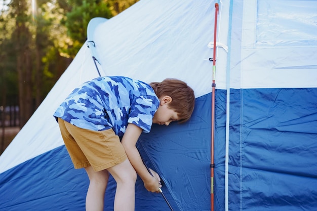 Cute little caucasian boy helping to put up a tent Family camping concept